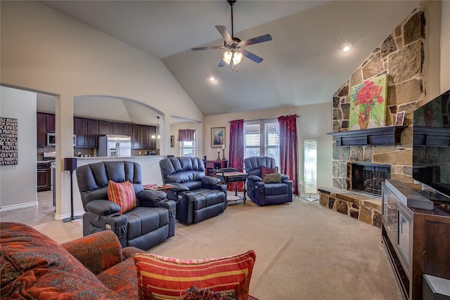 living area with arched walkways, a fireplace, light carpet, ceiling fan, and high vaulted ceiling