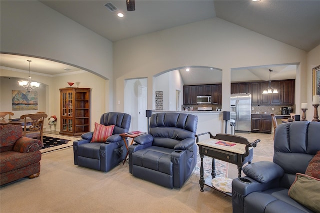 living area featuring a chandelier, arched walkways, visible vents, and high vaulted ceiling