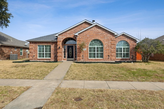 traditional home featuring brick siding, a front lawn, a shingled roof, and central air condition unit