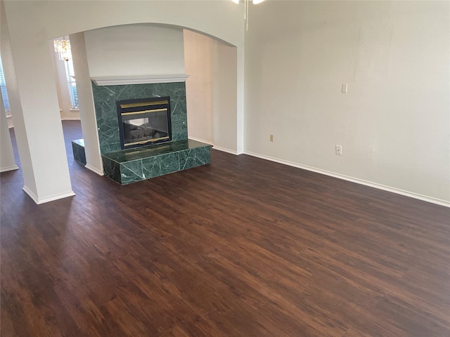 unfurnished living room with a premium fireplace, baseboards, and dark wood-type flooring