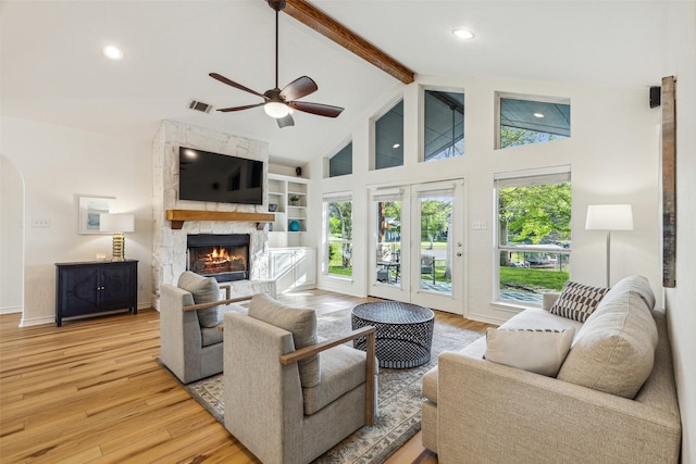 living room with high vaulted ceiling, light wood-type flooring, a fireplace, and beam ceiling