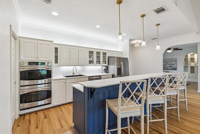 kitchen with arched walkways, a breakfast bar area, a sink, visible vents, and appliances with stainless steel finishes