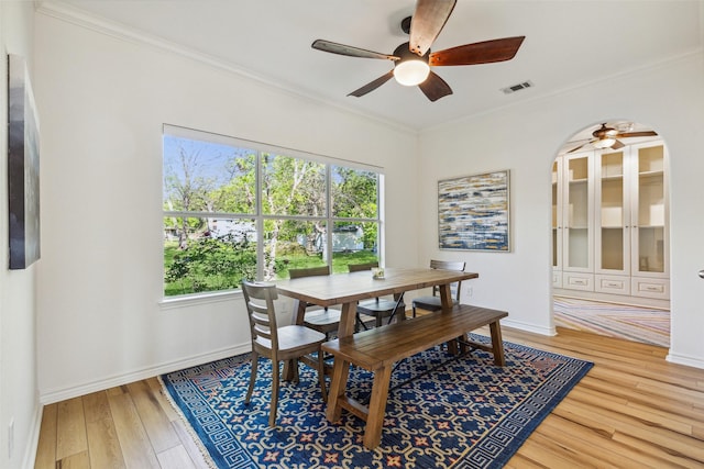 dining space with a healthy amount of sunlight, crown molding, visible vents, and light wood finished floors