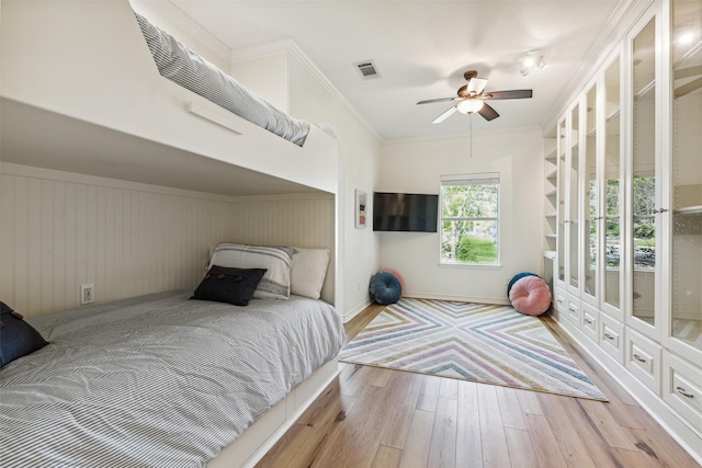 bedroom with ornamental molding, a ceiling fan, visible vents, and wood finished floors