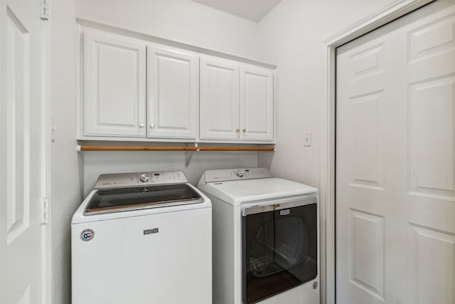 clothes washing area featuring cabinet space and separate washer and dryer