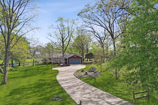 view of property's community featuring fence, concrete driveway, and a yard