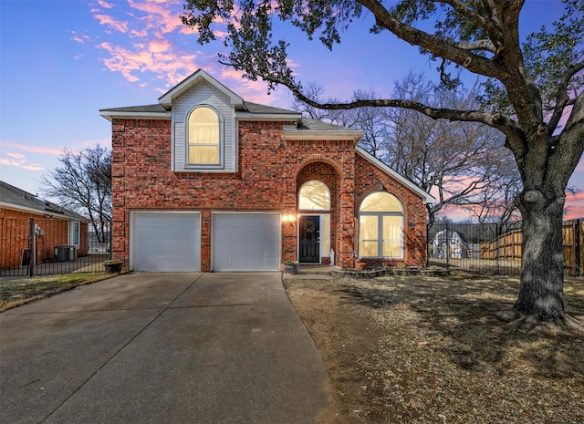 traditional home featuring brick siding, fence, central AC unit, a garage, and driveway