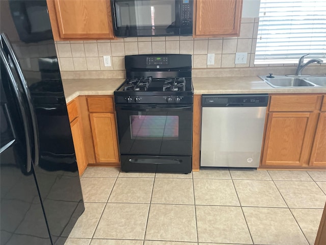 kitchen with black appliances, backsplash, a sink, and light countertops