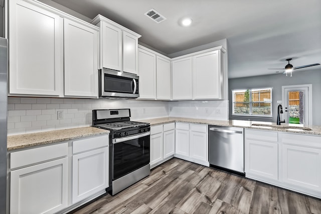 kitchen with wood finished floors, a sink, visible vents, white cabinetry, and appliances with stainless steel finishes