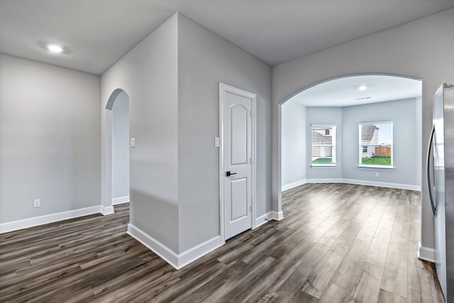 interior space with arched walkways, dark wood-style floors, and baseboards