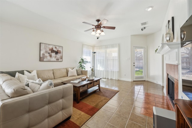 living room with visible vents, baseboards, a tiled fireplace, ceiling fan, and tile patterned floors