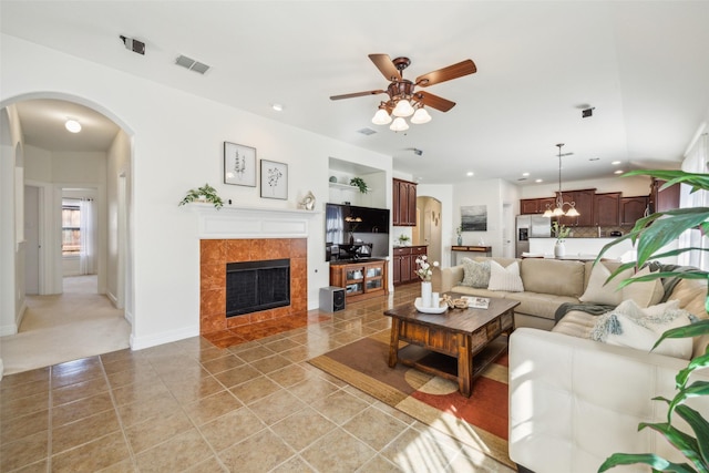 living area featuring arched walkways, light tile patterned floors, recessed lighting, visible vents, and a tile fireplace