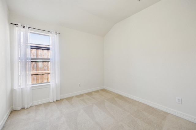 spare room featuring carpet floors, a healthy amount of sunlight, vaulted ceiling, and baseboards