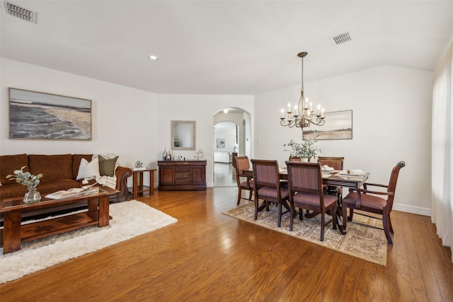 dining space with arched walkways, visible vents, and wood finished floors