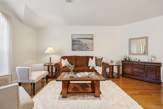 living area with vaulted ceiling and wood finished floors