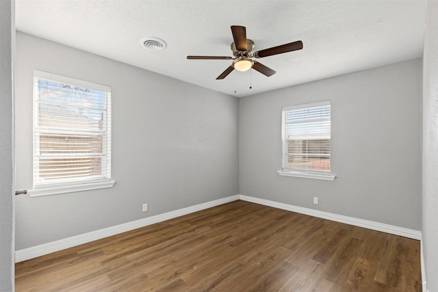 spare room featuring wood finished floors, visible vents, and baseboards