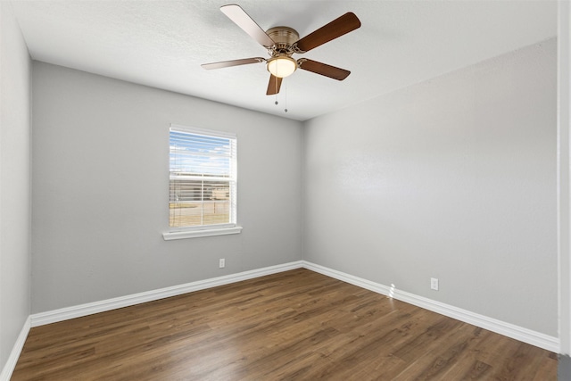 empty room featuring dark wood-style flooring, a ceiling fan, and baseboards