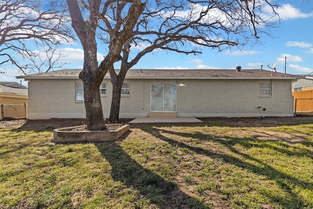 back of property featuring brick siding, a lawn, a patio area, and fence