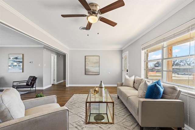 living room featuring baseboards, visible vents, a ceiling fan, ornamental molding, and wood finished floors