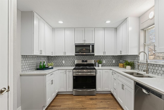 kitchen featuring stainless steel appliances, dark wood-style flooring, white cabinetry, and a sink