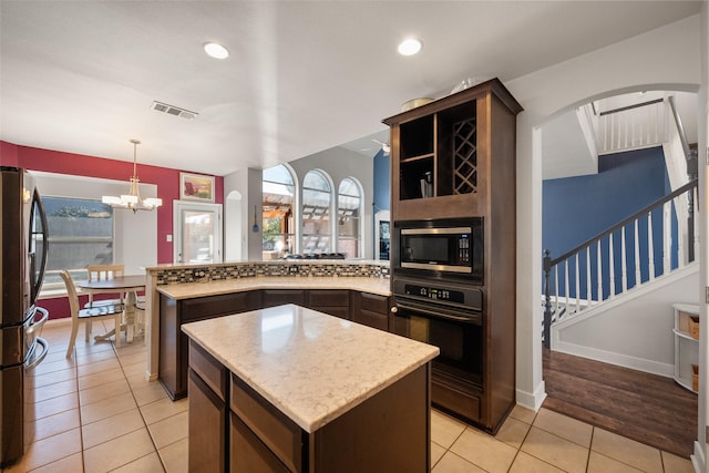 kitchen featuring a center island, stainless steel appliances, visible vents, dark brown cabinetry, and a peninsula