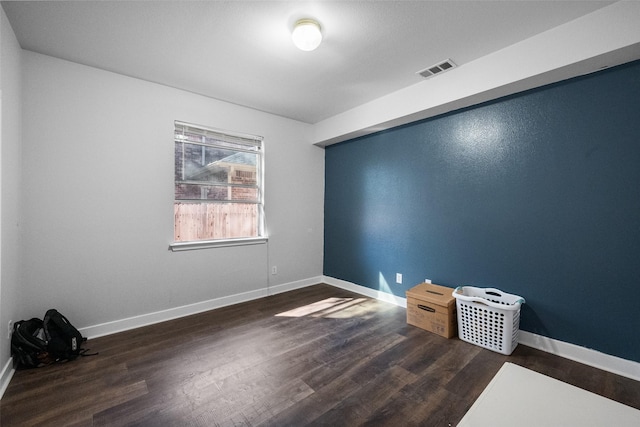 unfurnished room featuring visible vents, baseboards, and wood finished floors