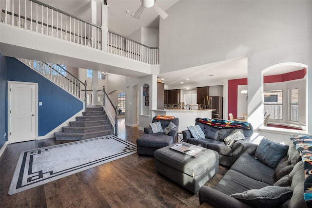 living area featuring stairway, baseboards, arched walkways, and wood finished floors