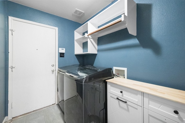 washroom featuring visible vents, cabinet space, and washer and clothes dryer