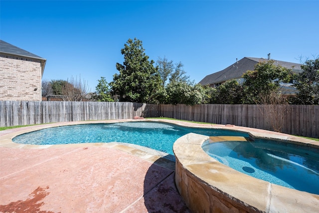 view of pool with a pool with connected hot tub, a fenced backyard, and a patio