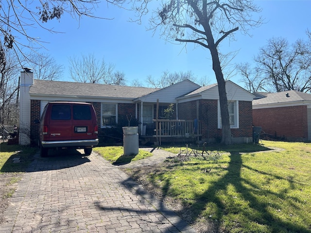 single story home with a porch, brick siding, a chimney, and a front lawn