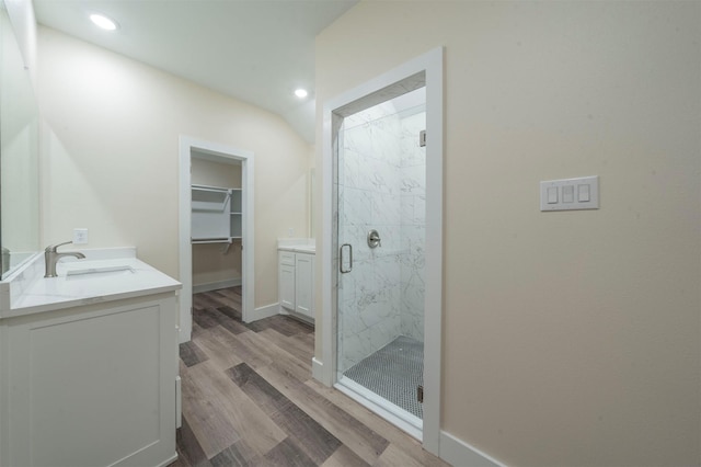 bathroom with a walk in closet, a marble finish shower, recessed lighting, vanity, and wood finished floors