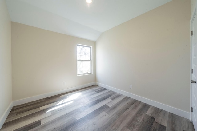 empty room with vaulted ceiling, wood finished floors, and baseboards