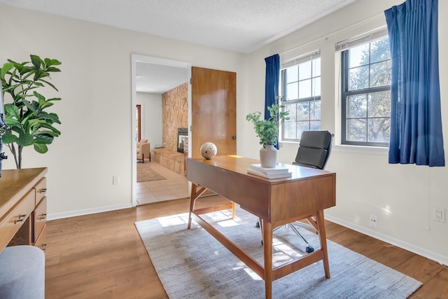 office area with a healthy amount of sunlight, a textured ceiling, baseboards, and wood finished floors