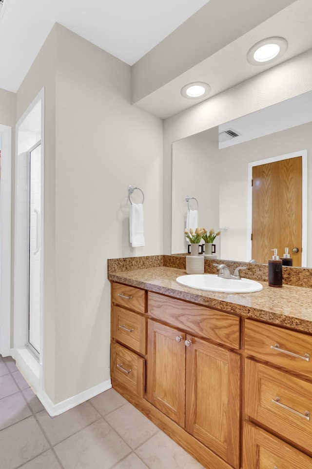 full bath with a stall shower, tile patterned flooring, vanity, and baseboards