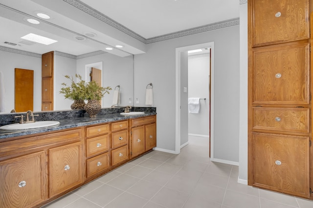 bathroom featuring double vanity, baseboards, ornamental molding, and a sink