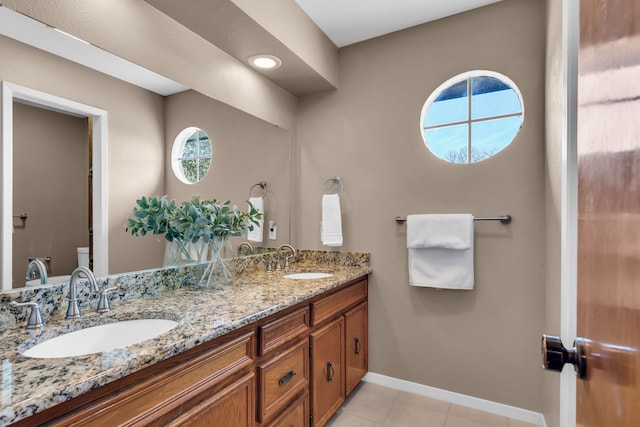 full bathroom featuring double vanity, tile patterned flooring, a sink, and baseboards