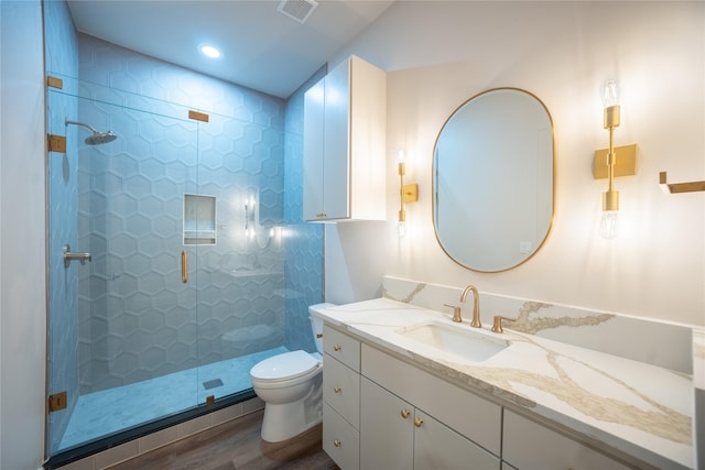 full bathroom with vanity, tiled shower, wood finished floors, and toilet