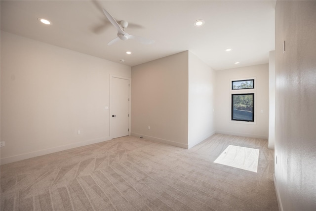 unfurnished room with ceiling fan, recessed lighting, light colored carpet, baseboards, and a glass covered fireplace