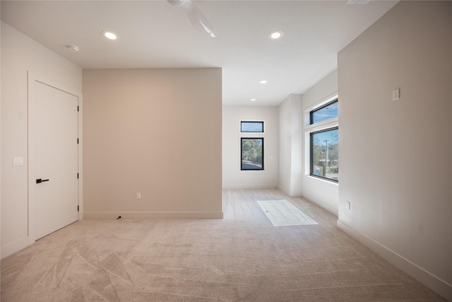 spare room featuring recessed lighting, light colored carpet, and baseboards