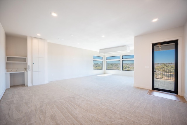 unfurnished living room with recessed lighting, light carpet, and baseboards