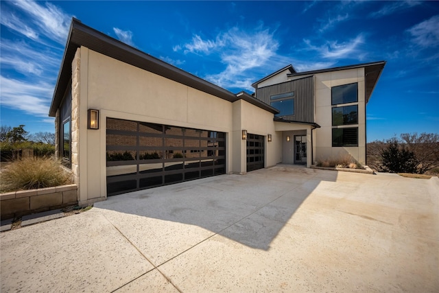 contemporary home with a garage, concrete driveway, and stucco siding