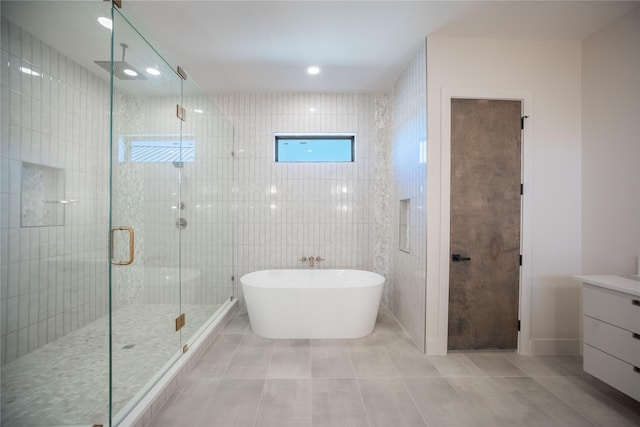 bathroom featuring tile walls, a soaking tub, a stall shower, vanity, and tile patterned floors