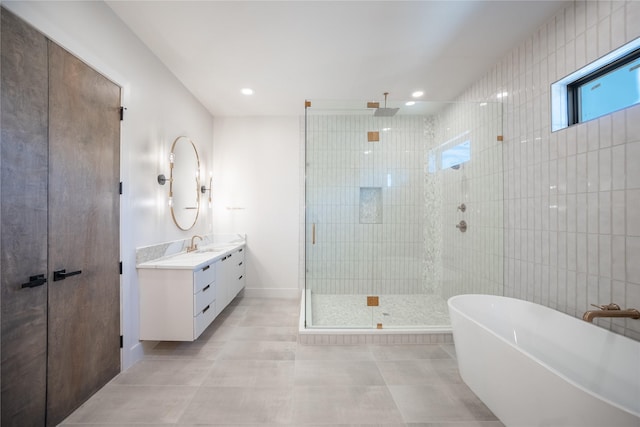 full bath with tile patterned floors, walk in shower, a freestanding bath, vanity, and tile walls