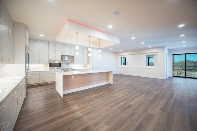 kitchen featuring visible vents, open floor plan, oven, range hood, and a sink