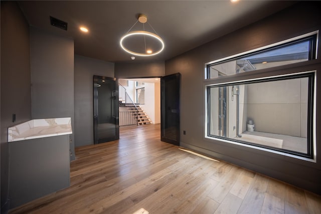 empty room featuring stairs, visible vents, wood finished floors, and recessed lighting