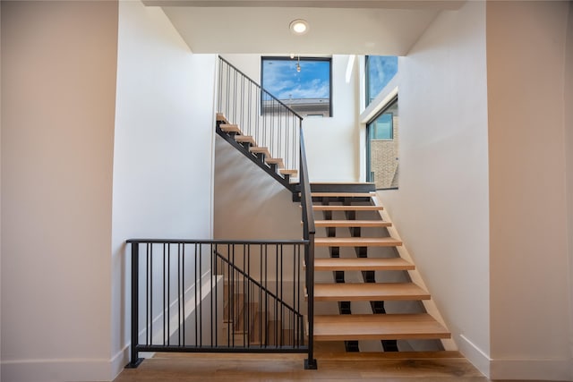 stairs featuring baseboards, wood finished floors, and recessed lighting