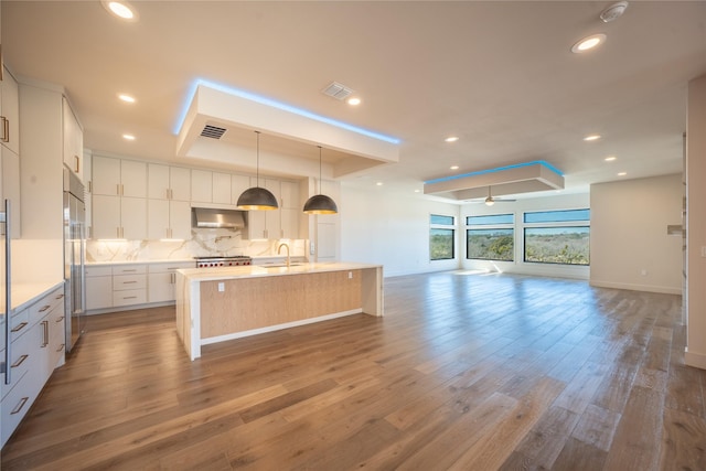 kitchen with open floor plan, visible vents, a sink, and under cabinet range hood