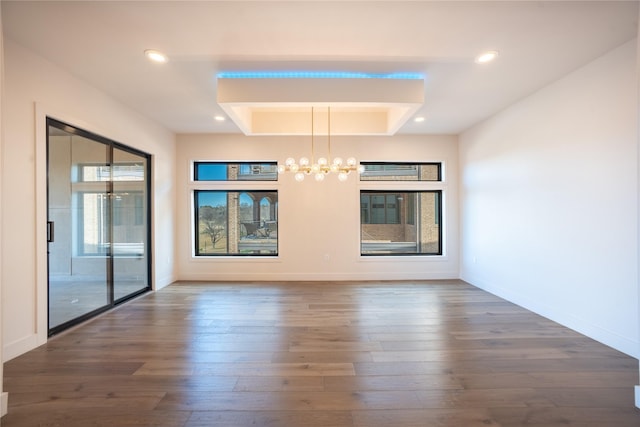 interior space featuring a tray ceiling, recessed lighting, wood finished floors, and baseboards