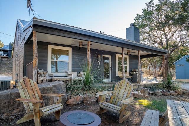 back of house featuring a ceiling fan, a chimney, metal roof, covered porch, and cooling unit