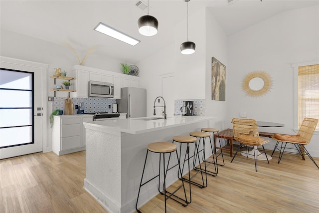 kitchen featuring appliances with stainless steel finishes, vaulted ceiling, a sink, and a kitchen breakfast bar